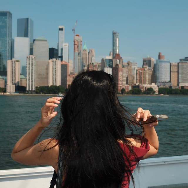 Alice standing on a boat facing New York City.