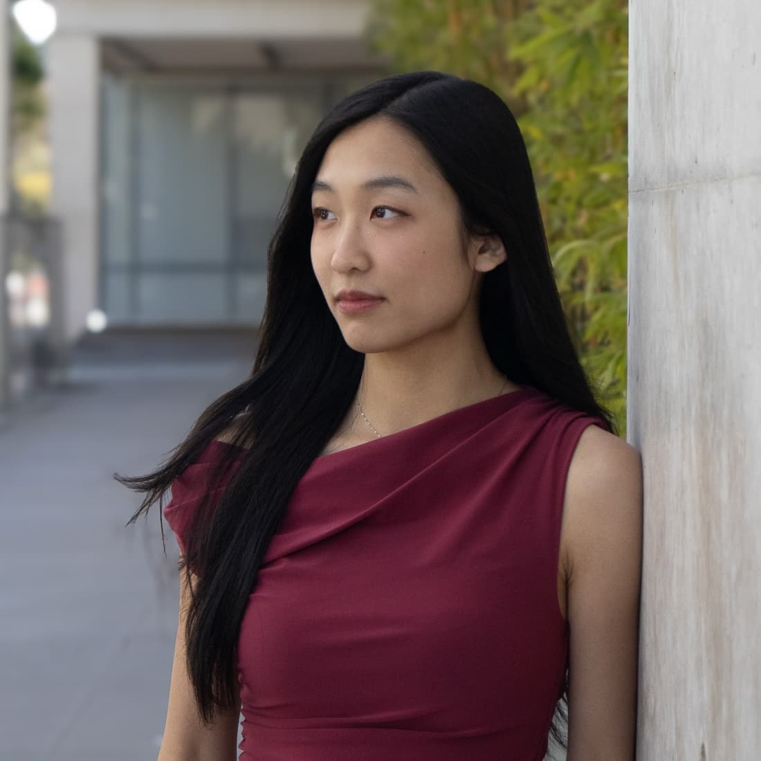 Alice Guo, wearing a maroon top, standing in a sunlit outdoor walkway