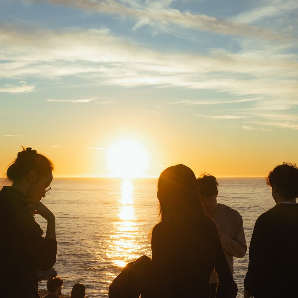 Alice smiling in front of an ocean sunset